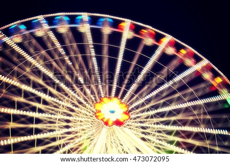 Blurred abstract background made of ferris wheel at night, vintage toned long exposure picture.