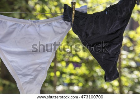 Black and white woman's panties dry on the rope in the summer in the day
