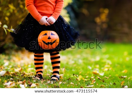 Little girl in witch costume playing in autumn park. Child having fun at Halloween trick or treat. Kids trick or treating. Toddler kid with jack-o-lantern. Children with candy bucket in fall forest. Royalty-Free Stock Photo #473115574