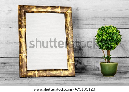 blank picture frame with artificial plant on old wood