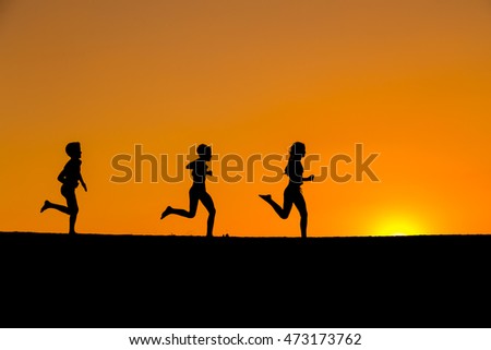 silhouette of three running kids against sunset