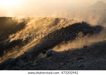 Toxic gases in the sunset seen from the crater of Vulcano, an active volcano in Lipari Islands. People in the background are hiking on the trail.