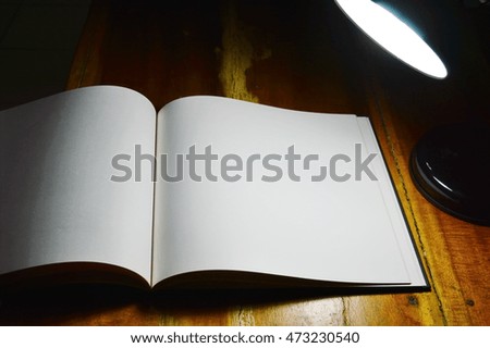 white paper book and reading lamp on wooden table in the night