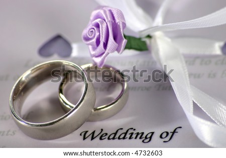 wedding bands sitting on wedding invitation/program with decorative flowers