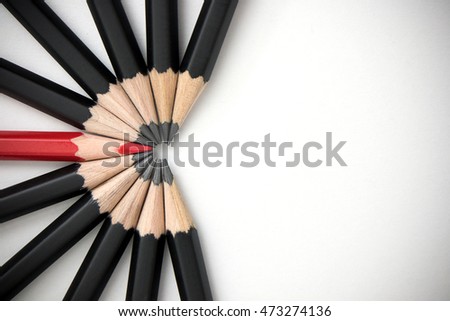 The red pencil is prominent and is surrounded by a black pencil. Leadership, uniqueness, think different, teamwork business success Royalty-Free Stock Photo #473274136