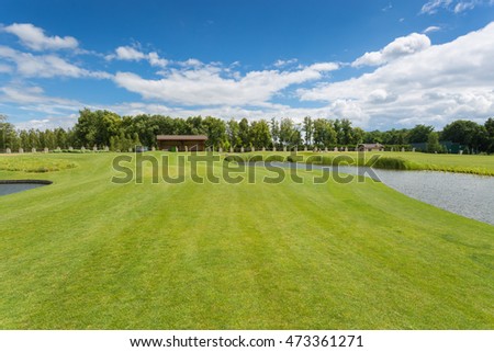 Beautiful golf course with perfect green grass and water hindrance at bright sunny day