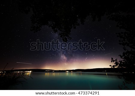 Night stars landscape with trees , milky way and stars mirroring in a lake Bodensee