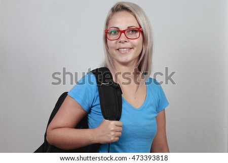 Young blonde student with red glasses and school bag