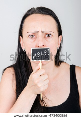 Woman asking for help, holding a small blackboard in front of her mouth with help written on in chalk.