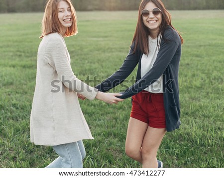 Two happy young women dance outdoors. Daylight