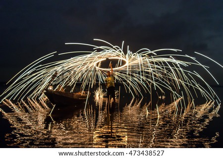 Showers of hot glowing sparks from spinning steel wool on the rock and beach