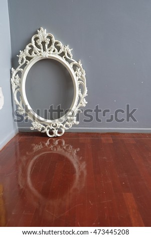 Vintage photo frame and reflection on wooden floor over grunge background
