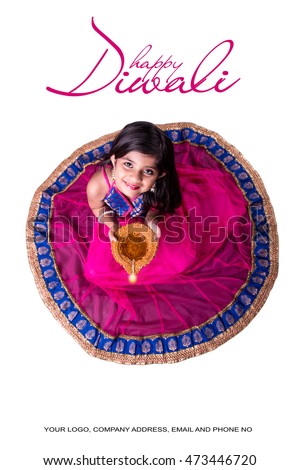 Cute little indian/asian girl in traditional wear holding a diya or Terracotta oil lamp on Diwali festival. top view over white background Royalty-Free Stock Photo #473446720
