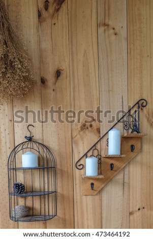 Candle and holder hanging on a rustic grunge wooden wall 