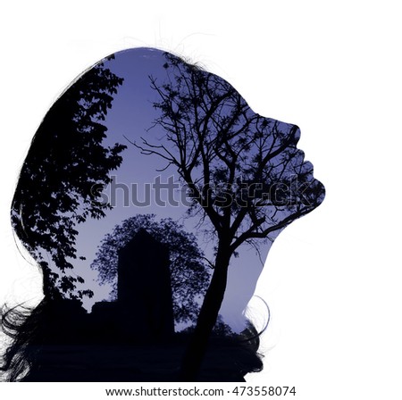 Silhouette of a female head (profile), framing fragment of mystical panorama with the tower in the background, double exposure. Toned photo, cold blue colors, dusk, bright background