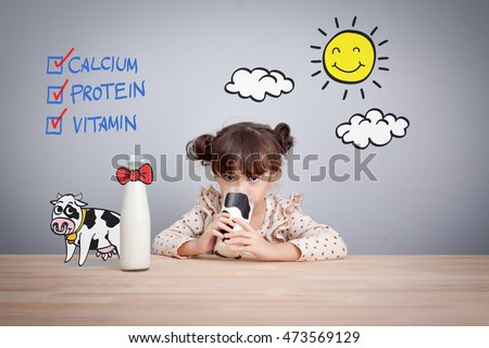 Adorable baby girl holding glass of milk and dringking milk