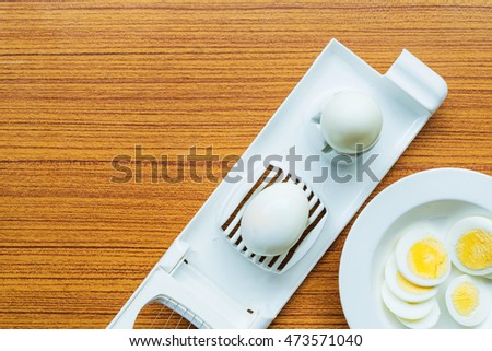 Picture of boiled eggs  in an egg slicer on wood table
