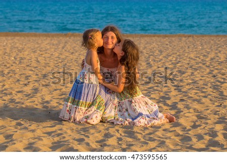 Children kissing and hugging mother at the beach. Happy family concept.
