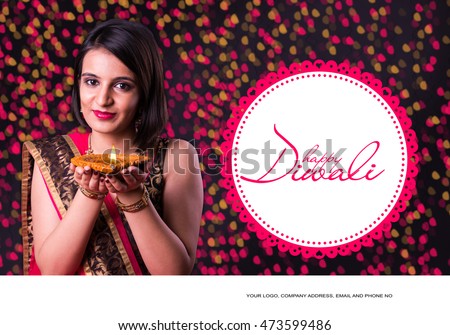 happy diwali greeting card showing indian beautiful Girl holding a diya or Terracotta Oil Lamp over black background Royalty-Free Stock Photo #473599486