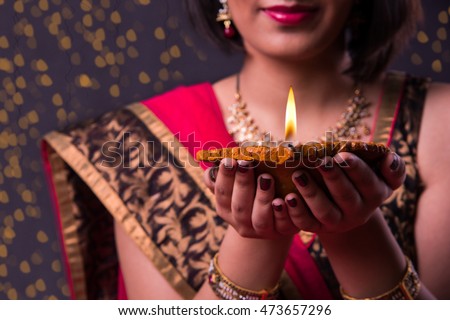 Happy Diwali Greeting card showing indian beautiful Girl holding a diya over black background Royalty-Free Stock Photo #473657296