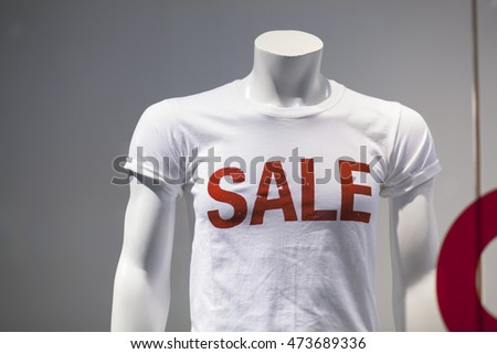 Window display with five mannequins wearing t-shirts with text Sale