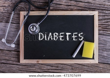 Stethoscope and Chalk board with inscription diabetes on wooden background. Medical concept