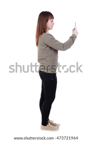 back view of standing young beautiful woman using a mobile phone. girl watching. Isolated over white background. she is cancer and makes selfie phone.