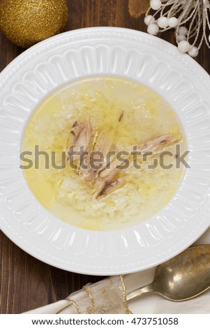 chicken broth with rice and chicken in white dish on brown wooden background