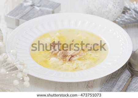 chicken broth with rice and chicken in white dish on white wooden background