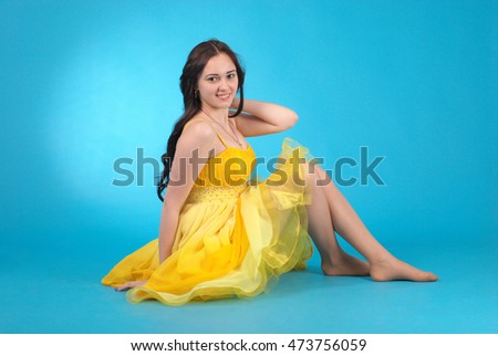 Young girl in ballroom dress on blue studio background.