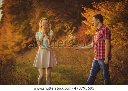 Man gives bouquet of field flowers to pretty blonde standing on the path