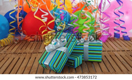Gift boxes on wooden table with background of colorful balloons and streamers