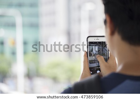 Asian man with mobile phone shooting photo