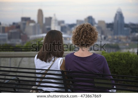 Two women watch the sunset over the Cincinnati skyline.
