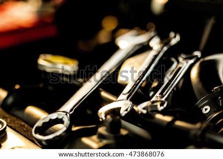 Mechanic hand checking and fixing a broken car in car service garage Royalty-Free Stock Photo #473868076