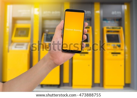 human hand hold smart phone, tablet, cellphone with virtual app internet banking on blurry Automatic Teller Machine Background, Online banking Concept.