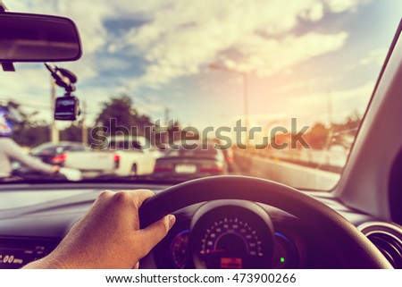 vintage tone image of people driving car on day time for background usage.(take photo from inside focus on driver hand)