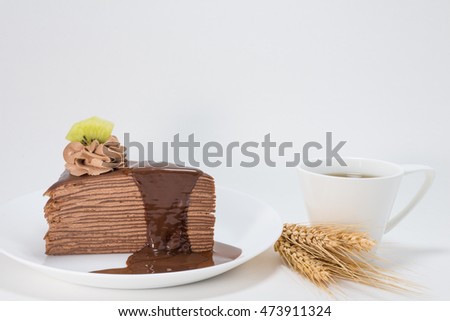 Chocolate crepe cake on white plate served with hot coffee, white background.