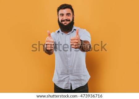 portrait of handsome smiling man isolated on yellow studio background posing to the camera and making funny faces and give likes