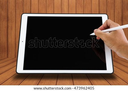 Close-up hand holding digital pen on digital tablet screen, with copy space, on wood texture background