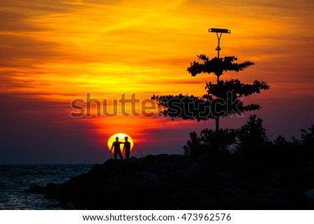 Silhouette of two male friends or couple hang out and enjoying the  beautiful view on nature at sunset.