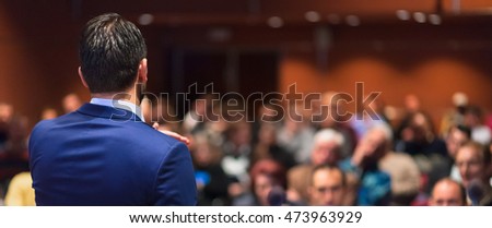 Rear view of speaker giving a talk on corporate Business Conference. Audience at the conference hall. Business and Entrepreneurship event. Panoramic composition. Royalty-Free Stock Photo #473963929