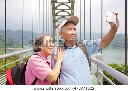 happy senior couple taking picture with smart phone selfie
