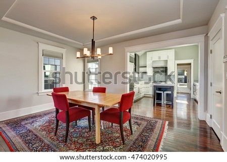 American dining room interior with table and red chairs on colorful rug, modern chandelier above the table. Northwest, USA