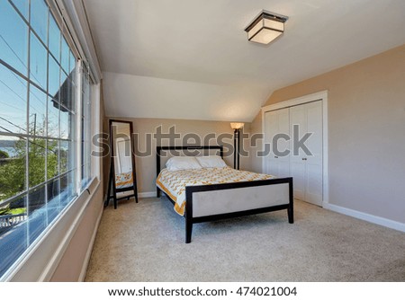 Simple yet elegant bedroom interior with vaulted ceiling, nice bed with yellow bedding, white doors closet and window view. Northwest, USA