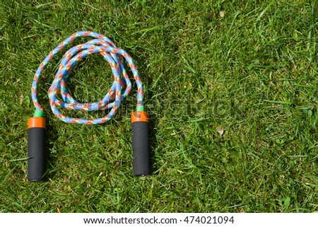 Skipping rope on green grass background. Fitness training in the open air with jumping rope