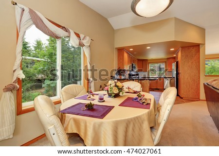 Soft beige dining room interior and nicely decorated table with some flowers and candles. And kitchen room behind. Northwest, USA