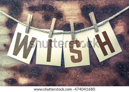 The word "WISH" stamped on cards and pinned to an old piece of twine over a rusted metal background.