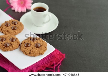 Chocolate chip cookies with cup of espresso, decorated with pink flower
