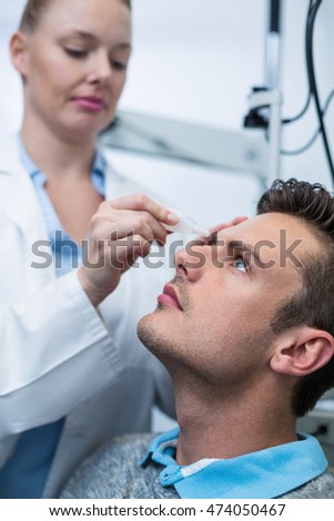 Female optometrist putting eye drop in patient eyes in ophthalmology clinic